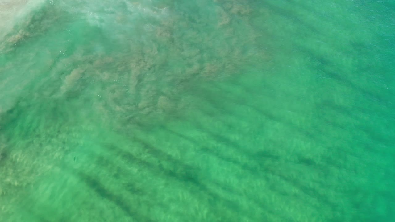 Turquoise-green water with light ripples and submerged shadows.