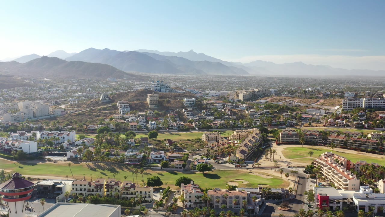 Aerial view of hillside condos below hazy mountains.