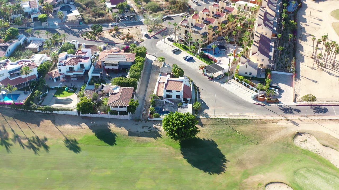 Drone view of resort buildings along a quiet curved street.