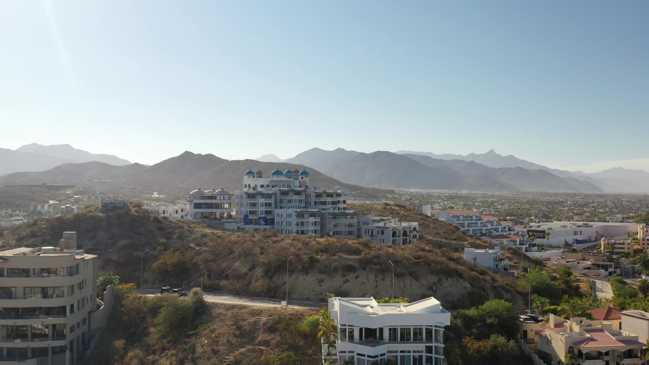 Wide hillside neighborhood with white homes and distant mountains