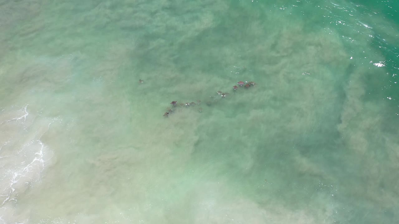 Teal shallows with several dark underwater patches near the upper right.