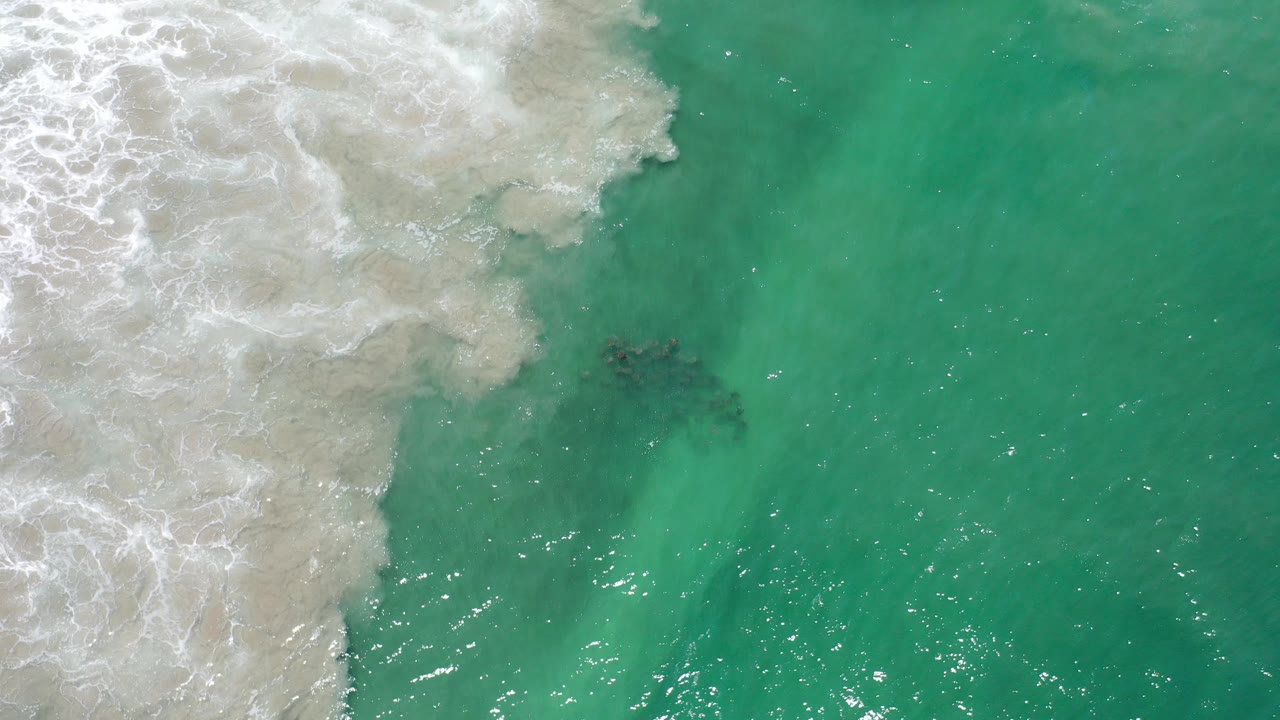 Overhead teal ocean with white surf entering from the left.