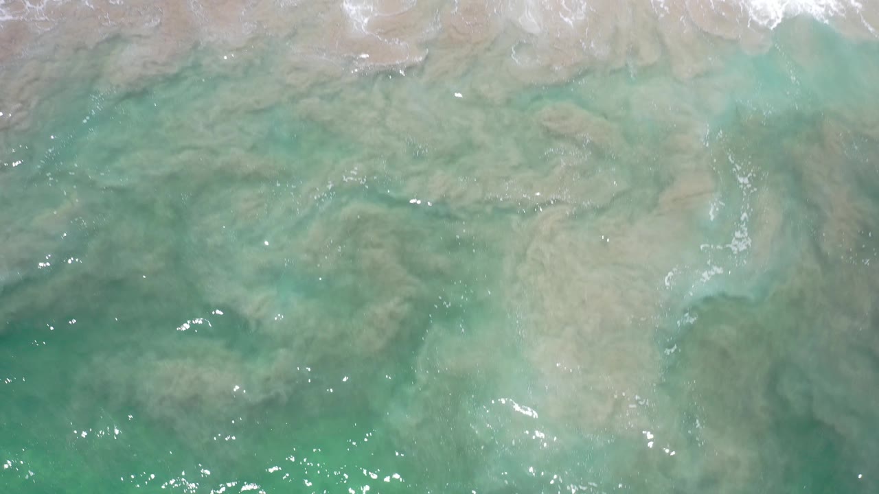 Turquoise water and sandy seabed near the edge of breaking surf.
