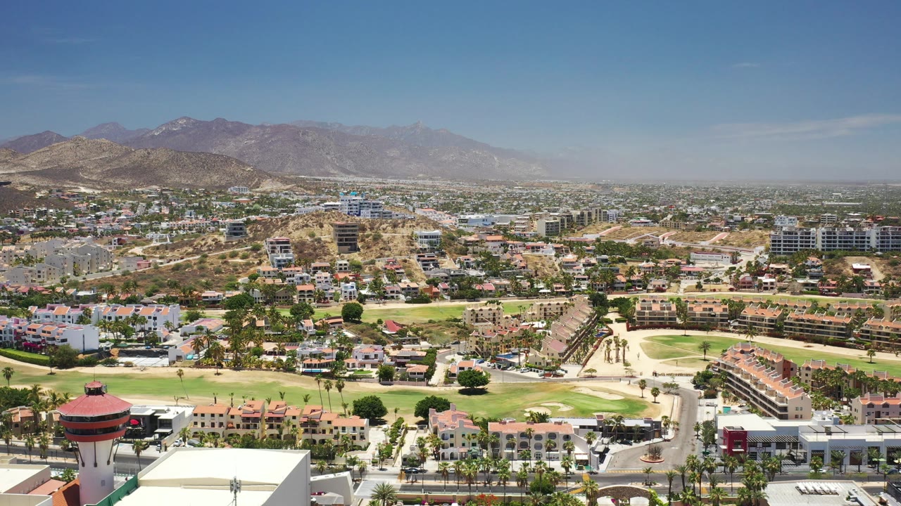 Aerial view of a resort town, green fairways, roads, and mountains.