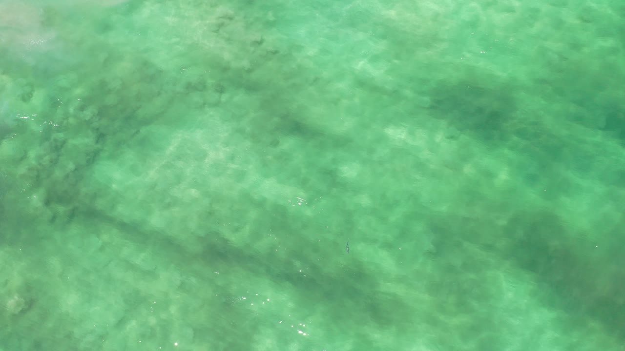 Overhead view of turquoise shallow water in Los Cabos, Mexico, with mottled sandy bottom texture and no visible people at the start of the clip.