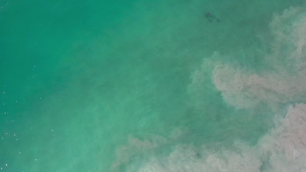 Bright aqua water with a cloudy pale sand formation near the right edge.