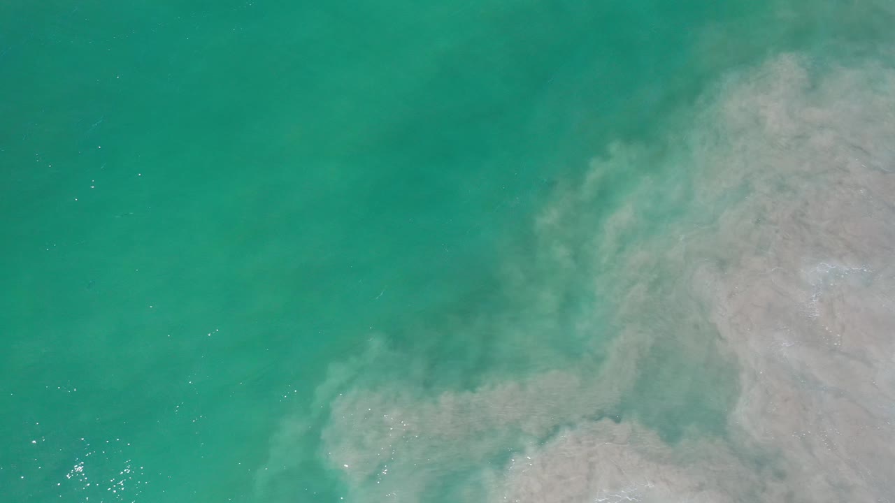 Green-blue water with pale foamy surf mass on the right.