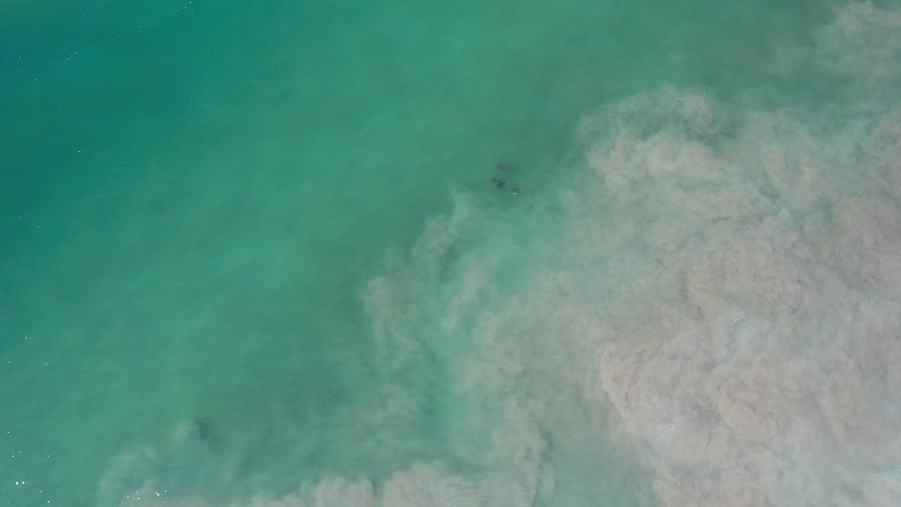 Top-down view of turquoise water in Los Cabos with a pale gray suspended cloud filling the right side and no visible people.