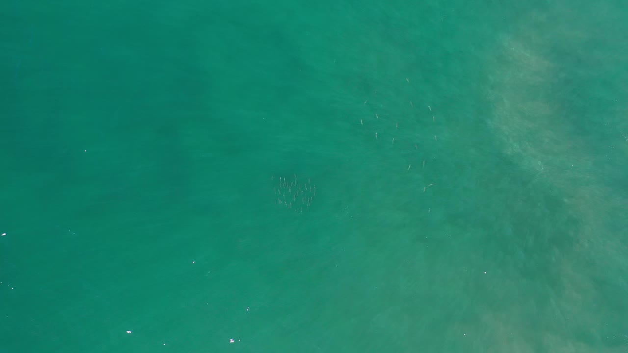 Aerial view of green ocean water with mottled cloudy areas.