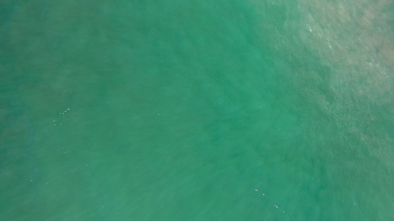 Teal-green water fills the first frame from Los Cabos, Mexico, with faint pale wave streaks and no visible people.