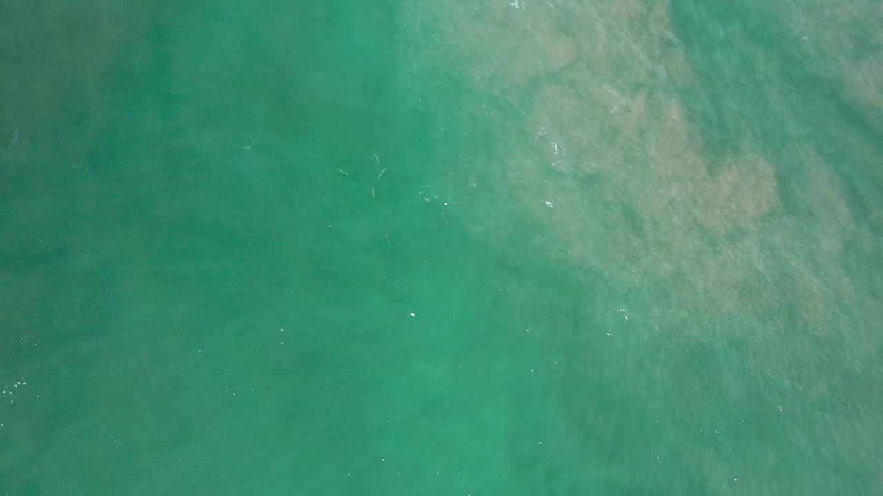 Clear green-blue water with sand texture underneath.