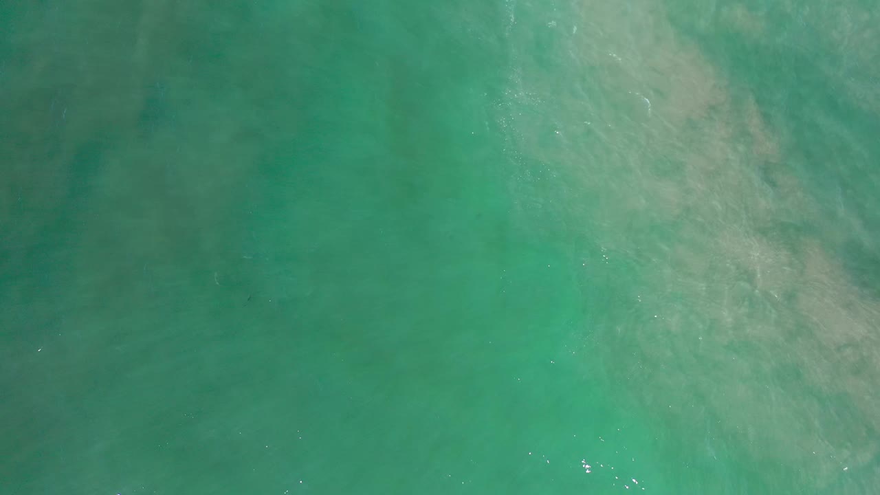 Overhead Los Cabos sea view with blue-green water, subdued cloudy areas below the surface, and no visible people.