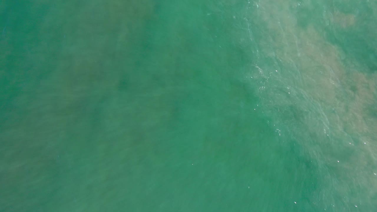 Turquoise water with soft pale patches and surface glints