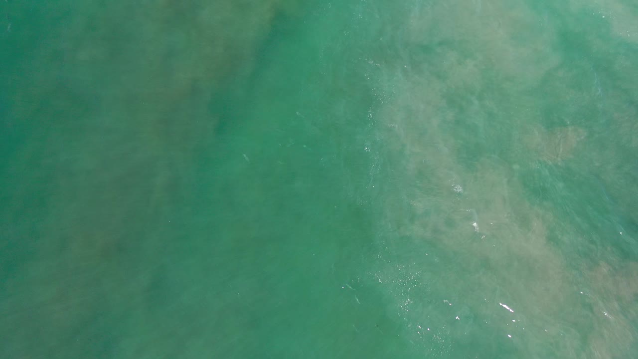 Overhead view of turquoise ocean water in Los Cabos, Mexico, with faint pale clouding below the surface and no visible people.