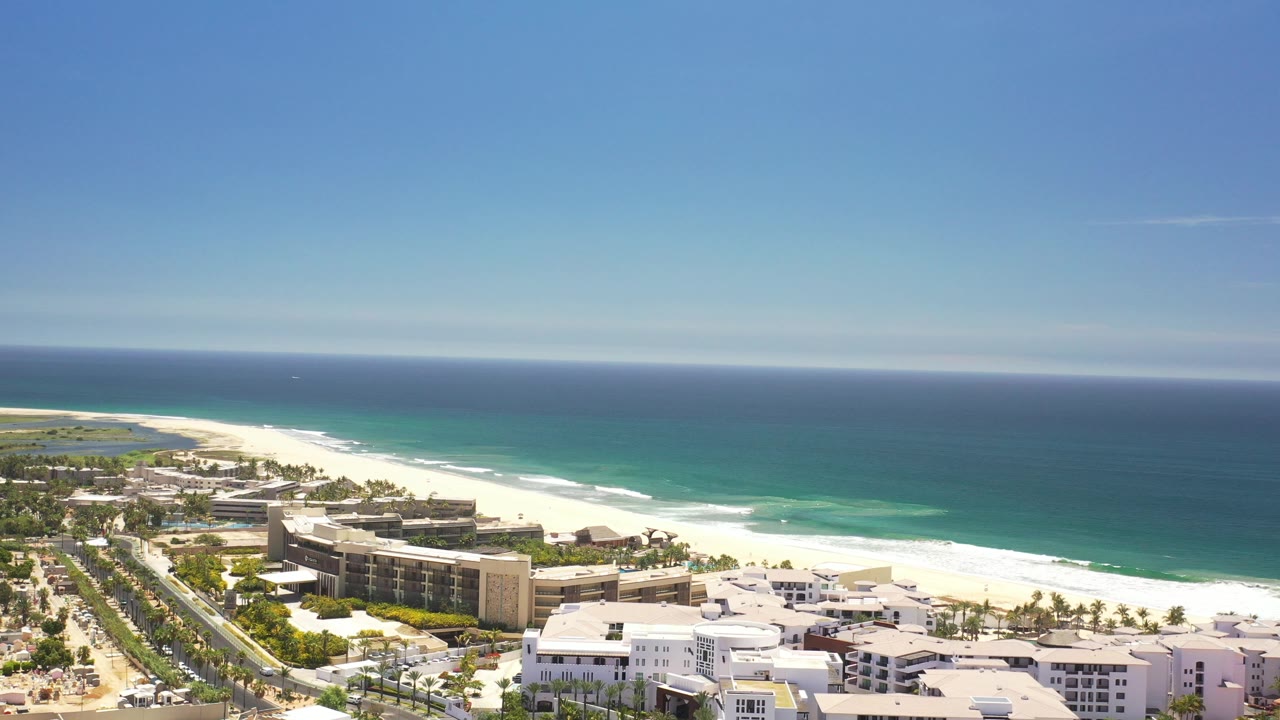 Aerial view of beachfront buildings, white sand, and blue sea.