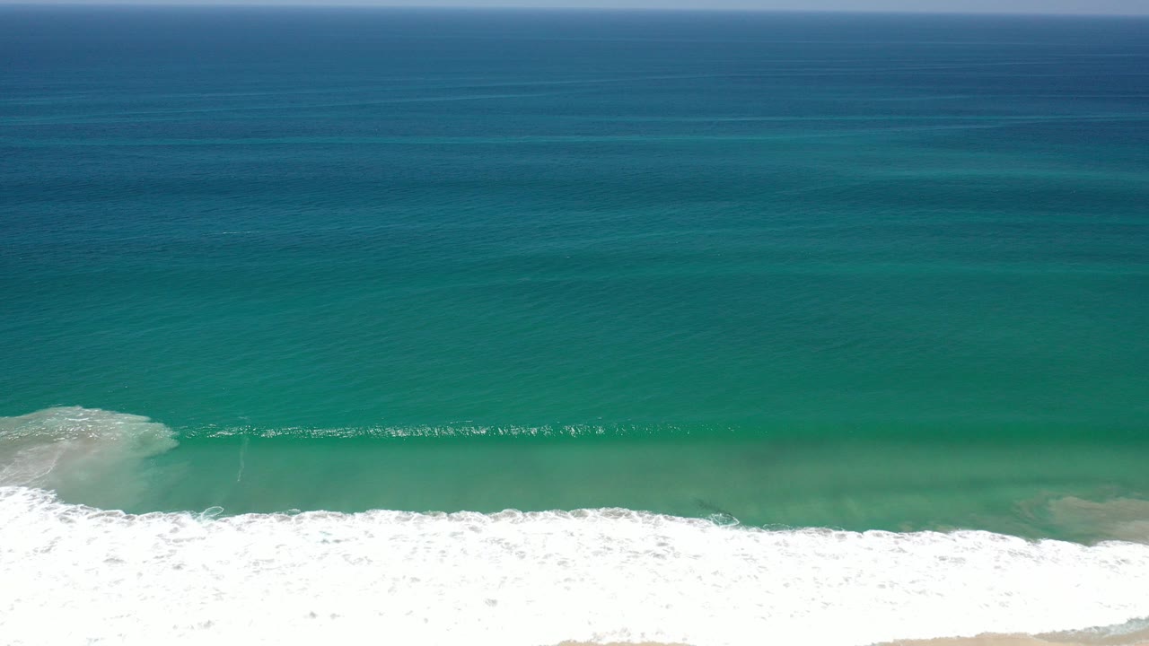 Turquoise ocean with white surf along the lower edge.