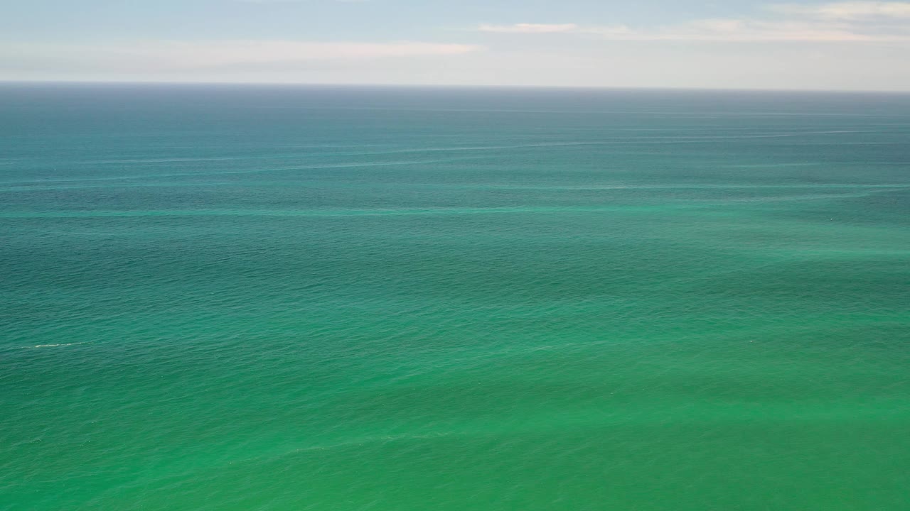 Teal-green ocean stretches toward a distant horizon in Los Cabos, Mexico, with faint ripples and no visible people.