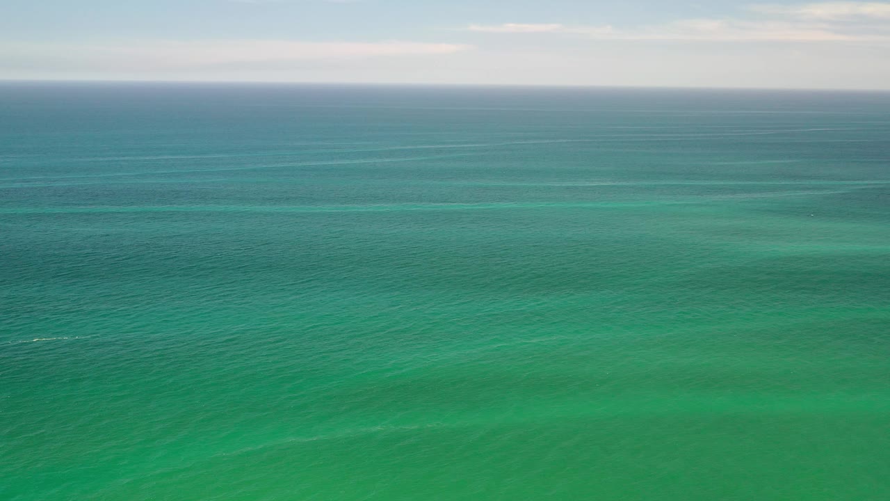 Open green sea with thin clouds above