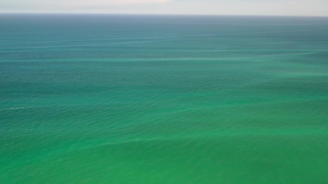 A high view over turquoise-green sea in Los Cabos, Mexico, showing layered surface texture and no visible people.