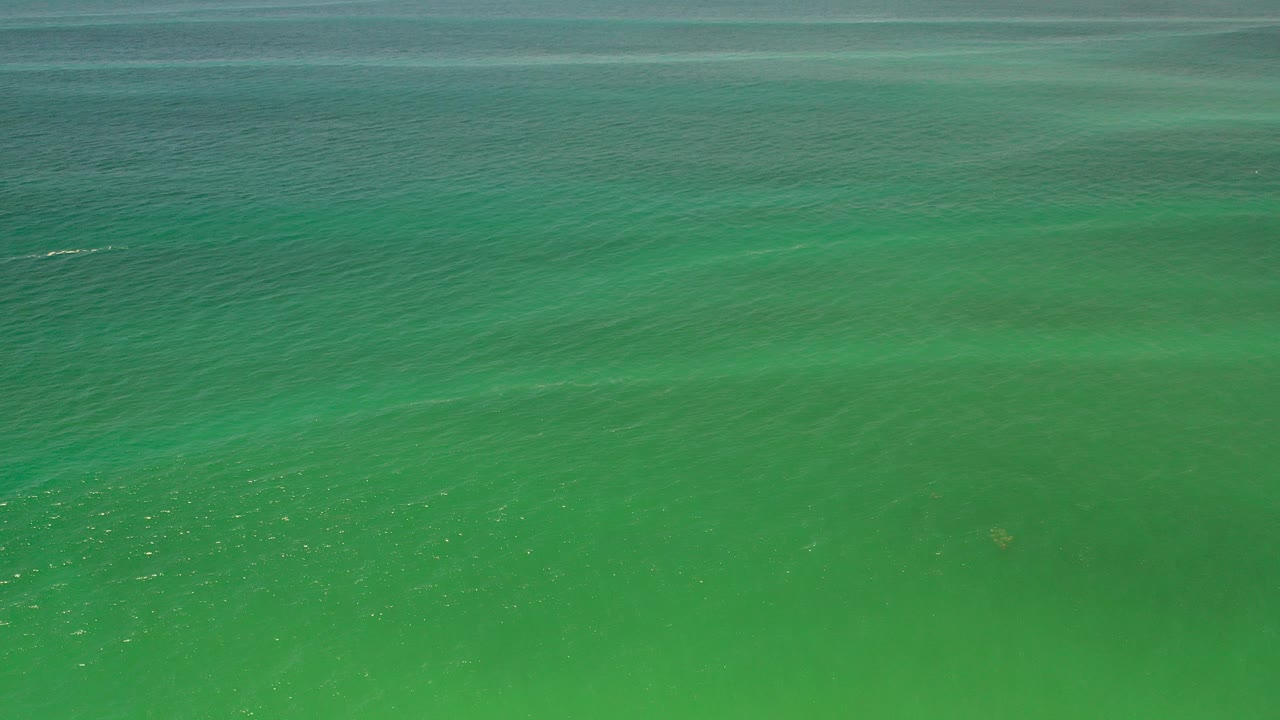 Blue-green ocean water in Los Cabos fills the frame at the start of the clip, with faint darker bands under the surface and no visible people.