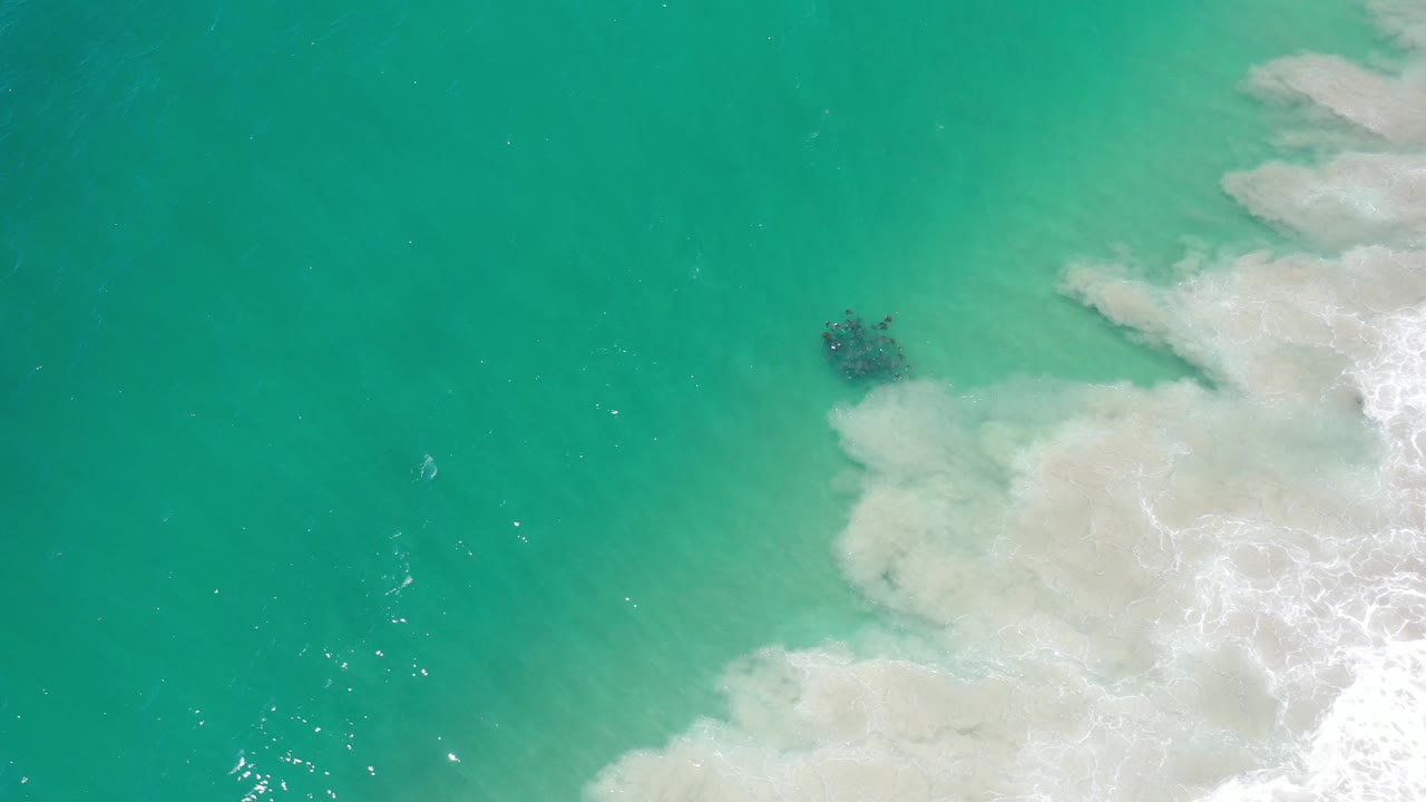 White surf curls into clear green water from the right.