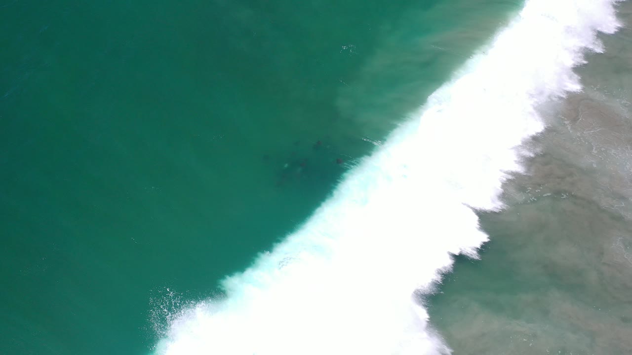 Overhead turquoise ocean with a diagonal white surf band.