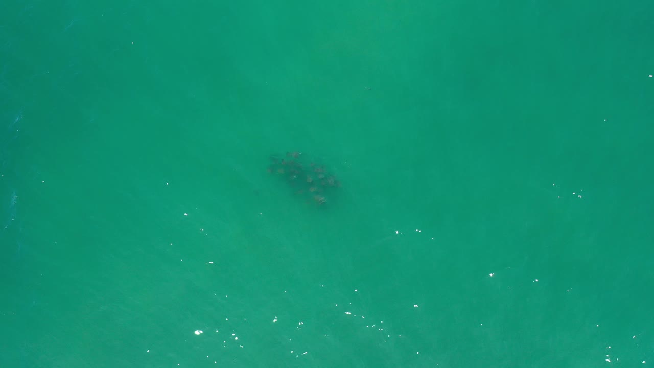 Aerial ocean surface with a dark patch near the top and small light reflections.
