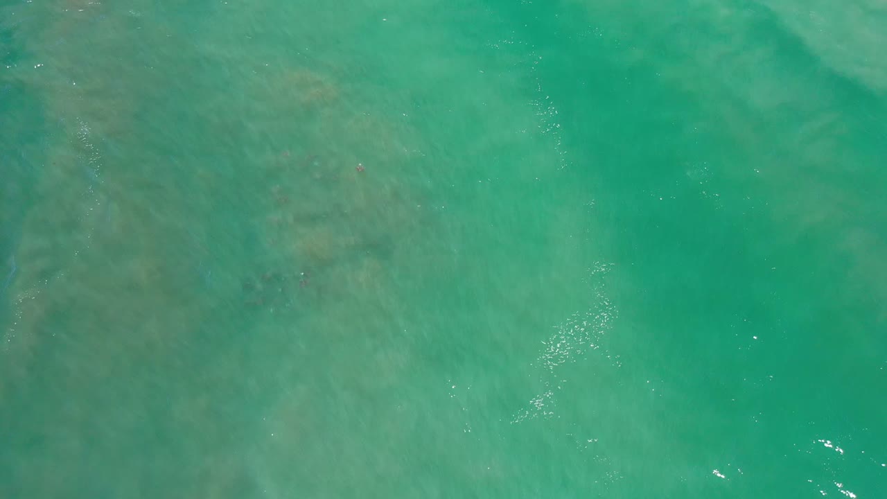 Overhead turquoise ocean water with darker submerged patches.