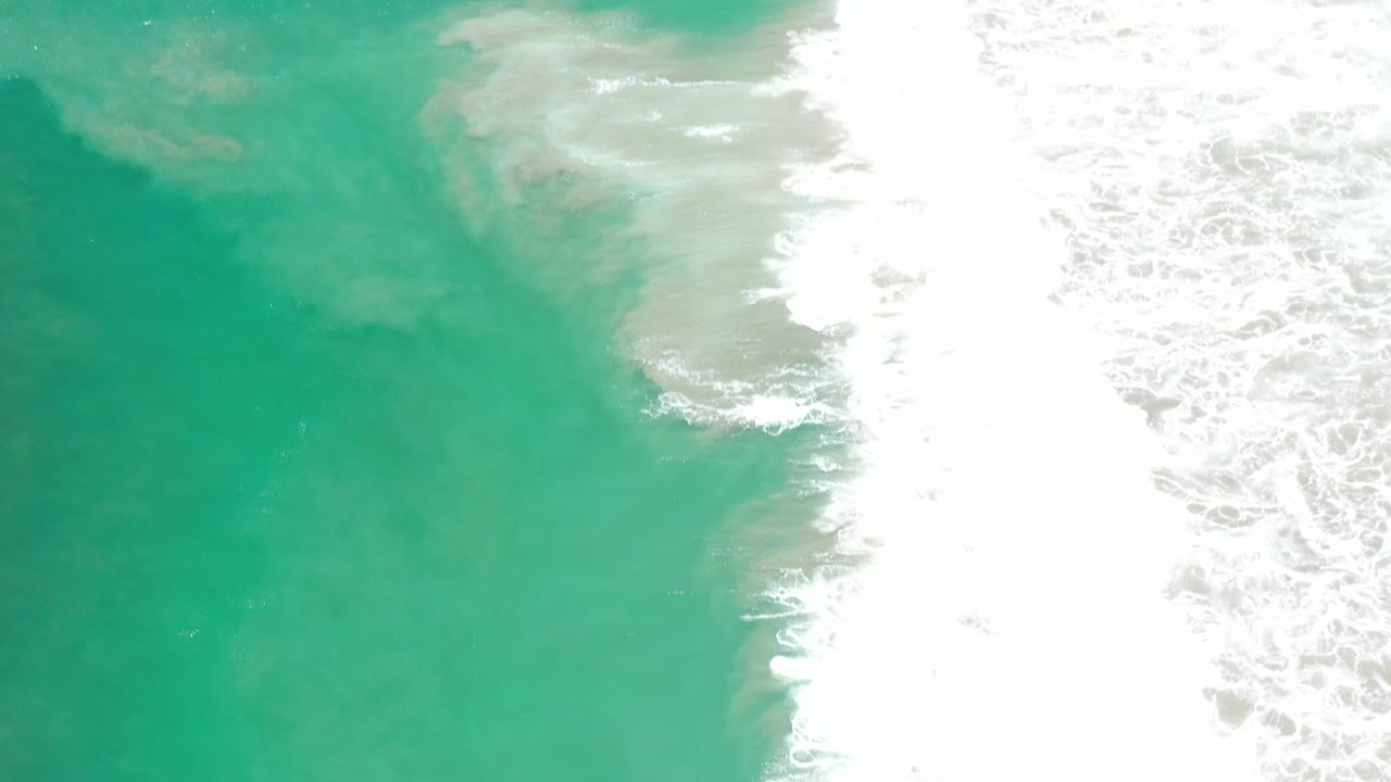 Turquoise ocean water with white surf breaking along the right side