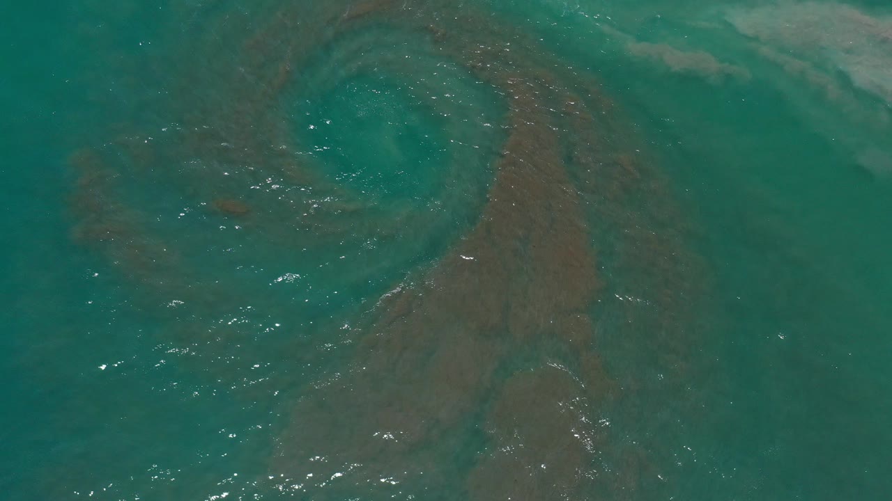 Turquoise ocean surface with a dark brown swirl beneath the water.