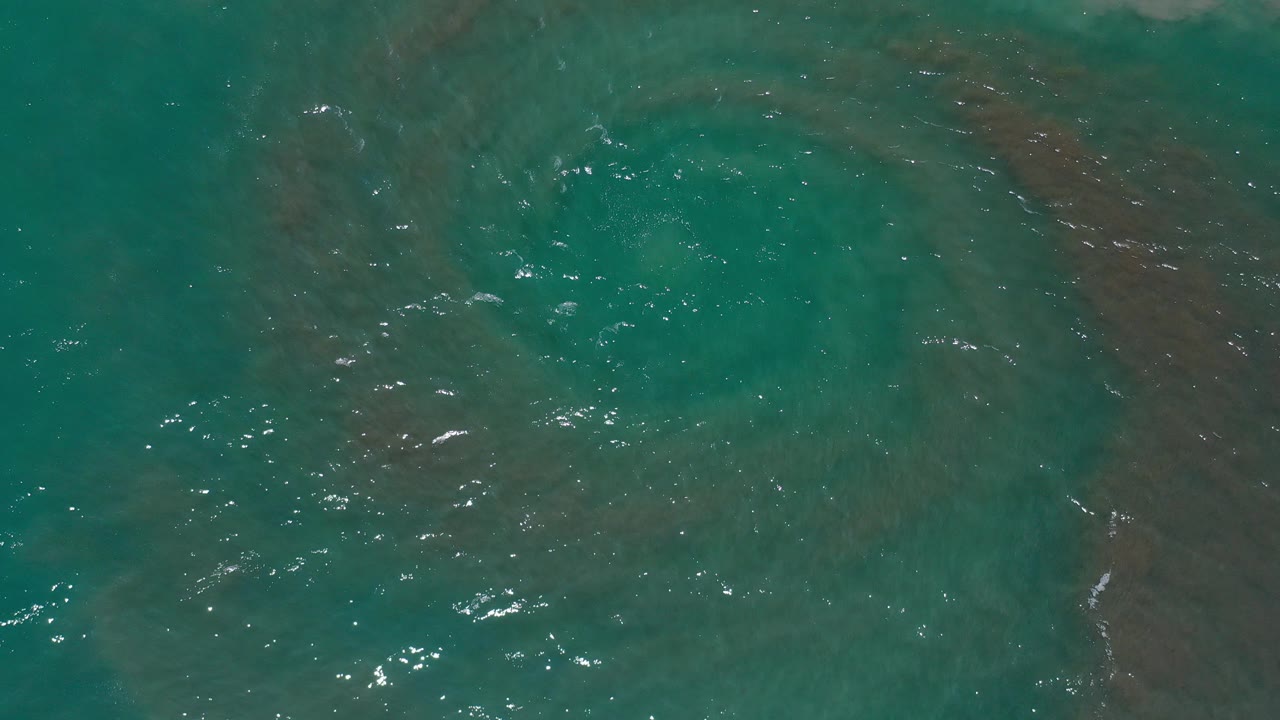 Overhead teal ocean water with darker eddy patches