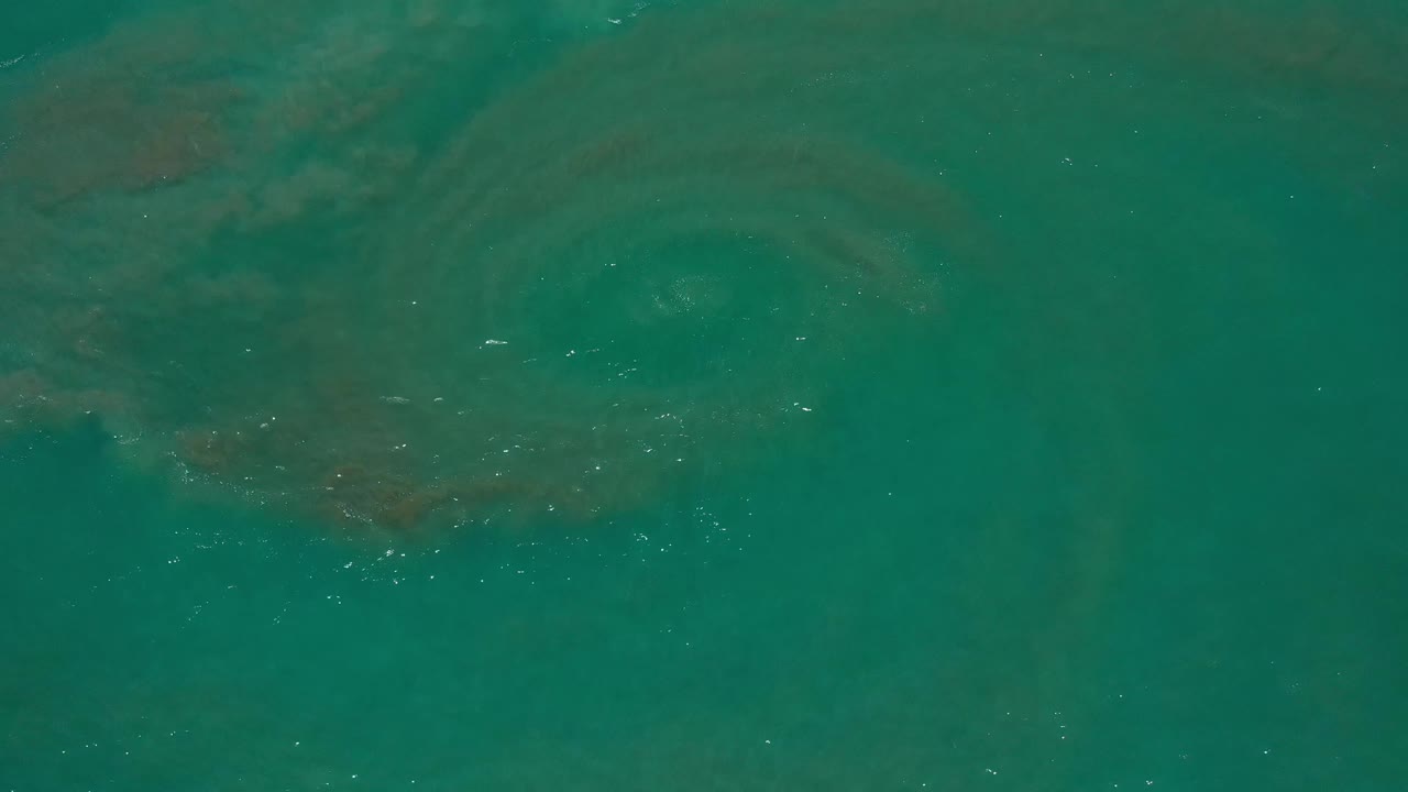 Aerial view of Los Cabos ocean water with a broad curved darker band crossing the upper part of the frame and no visible people.