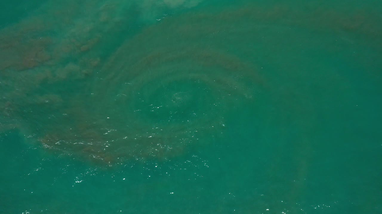 Top-down view of teal ocean water in Los Cabos, Mexico, with faint darker shapes under the surface and no visible people.