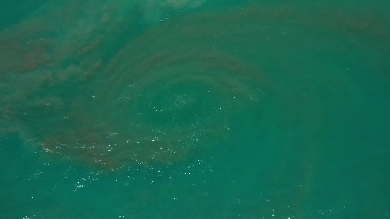 Teal Los Cabos ocean surface with darker underwater areas and scattered sun flecks, with no visible people.