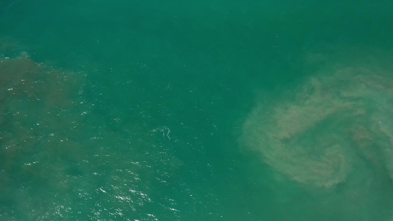 Overhead teal water with pale swirling disturbance