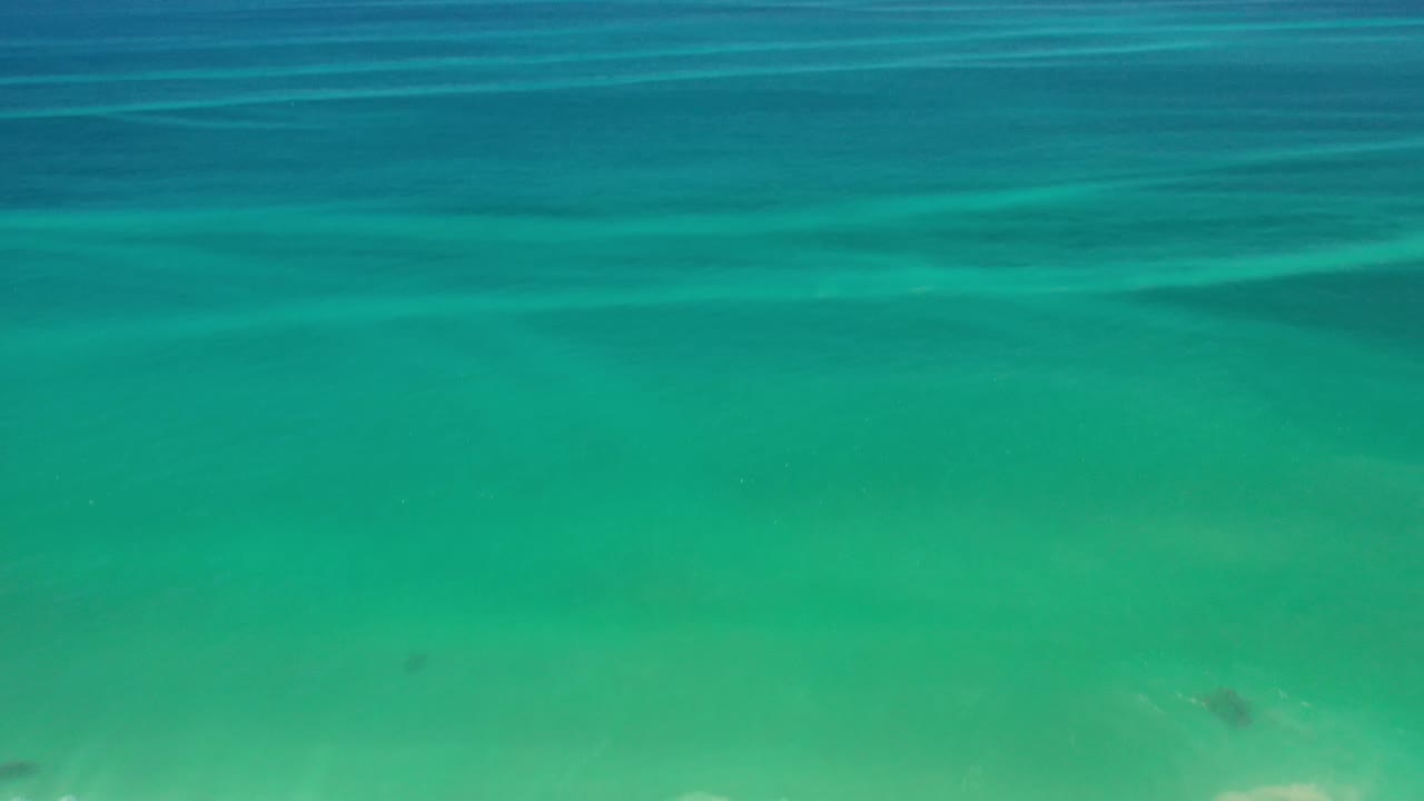 Aqua and teal ocean surface in Los Cabos, Mexico, with darker blue water across the upper frame and no visible people.