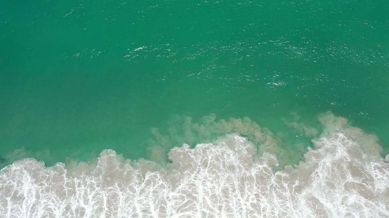 Green ocean water above a foamy shoreline