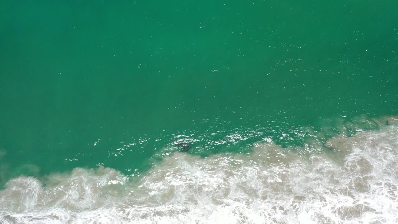 Turquoise-green ocean with white surf along the lower edge.