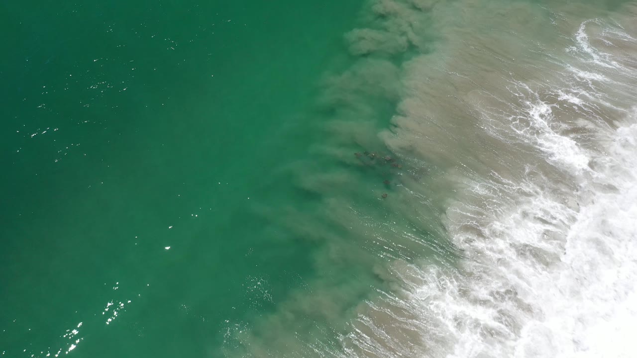 Turquoise water with surf breaking along the upper right edge.