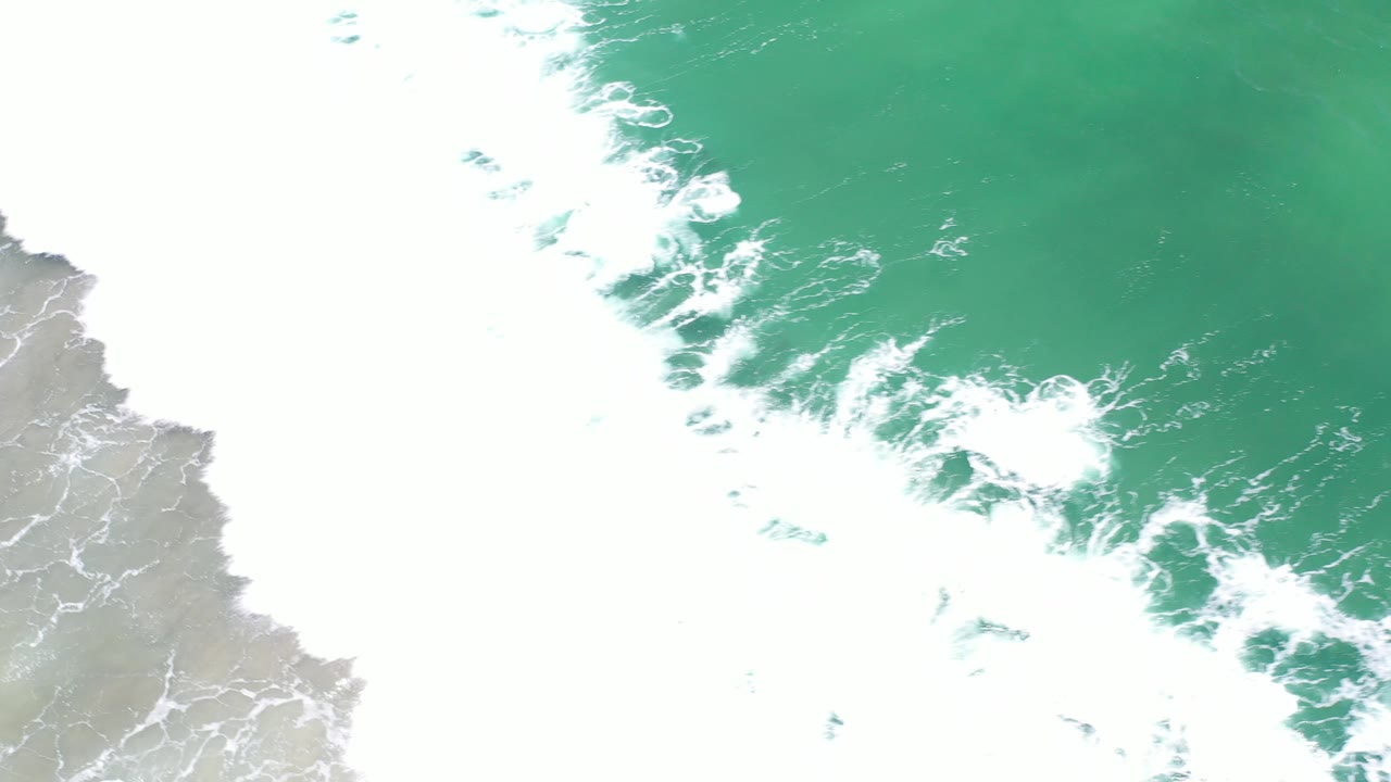 Aerial surf line with green water and white foam.