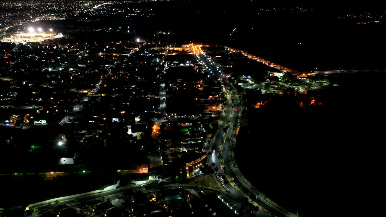 Aerial night traffic scene with a curved road in the foreground.