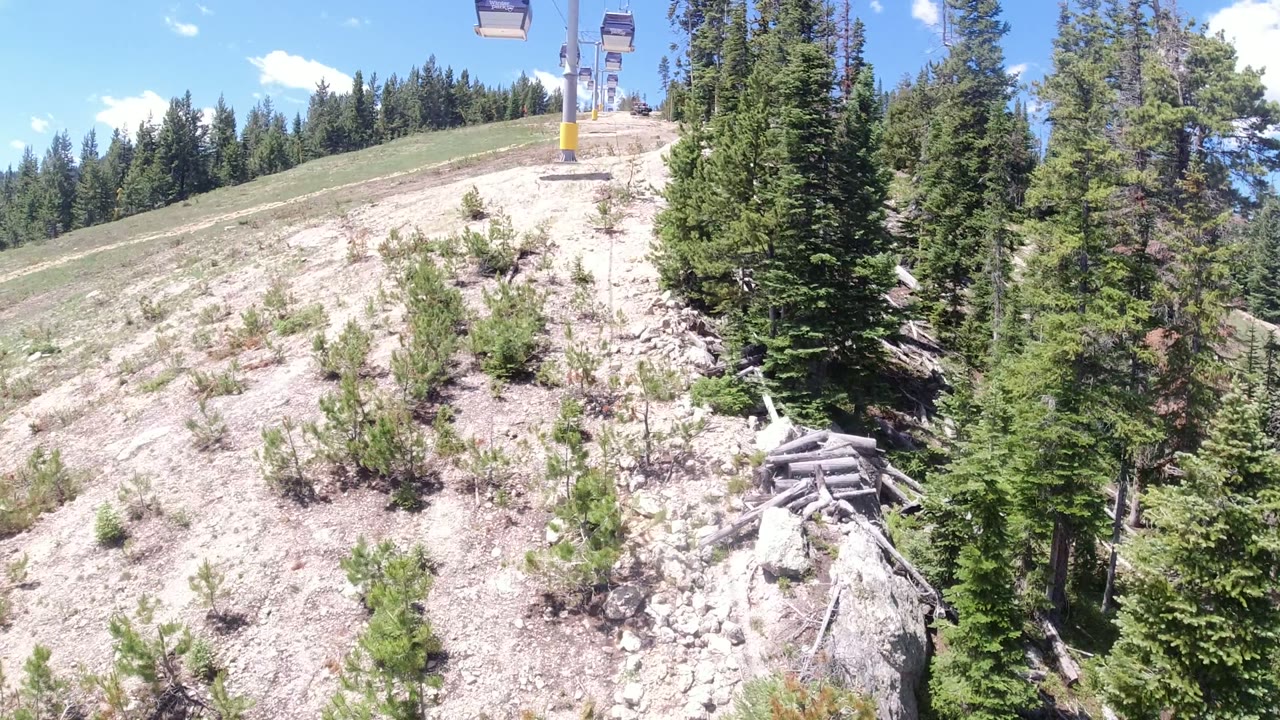 Winter Park, Colorado chairlift view over a pale cleared slope with evergreen forest on the right and no visible people.