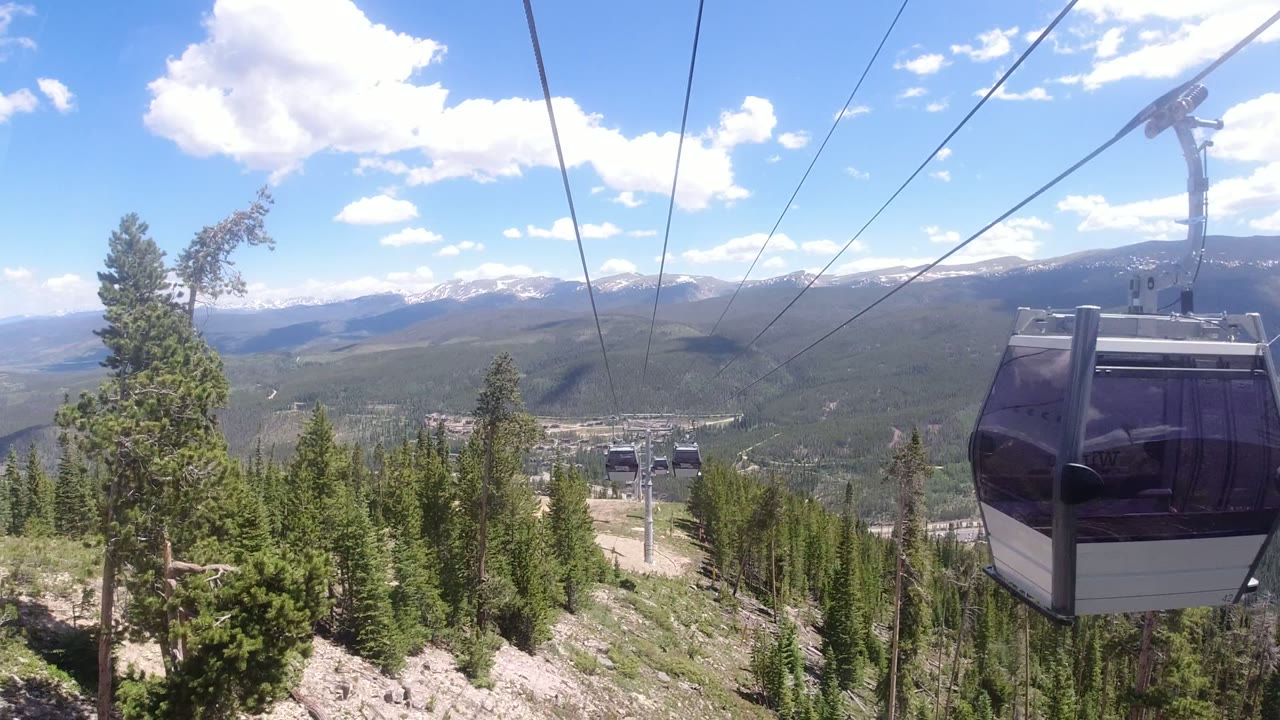 Gondola cabin near overhead lift cables above evergreen mountains
