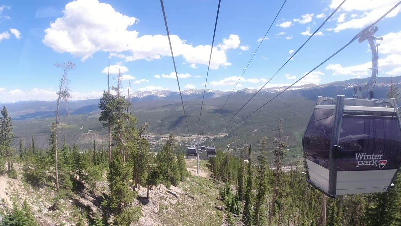 Cable lift over a forested mountainside with distant ridges.