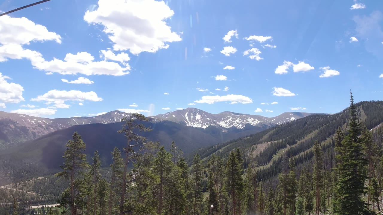 Winter Park, Colorado ridgelines and evergreen forest seen through a reflective cableway window, with no visible people.