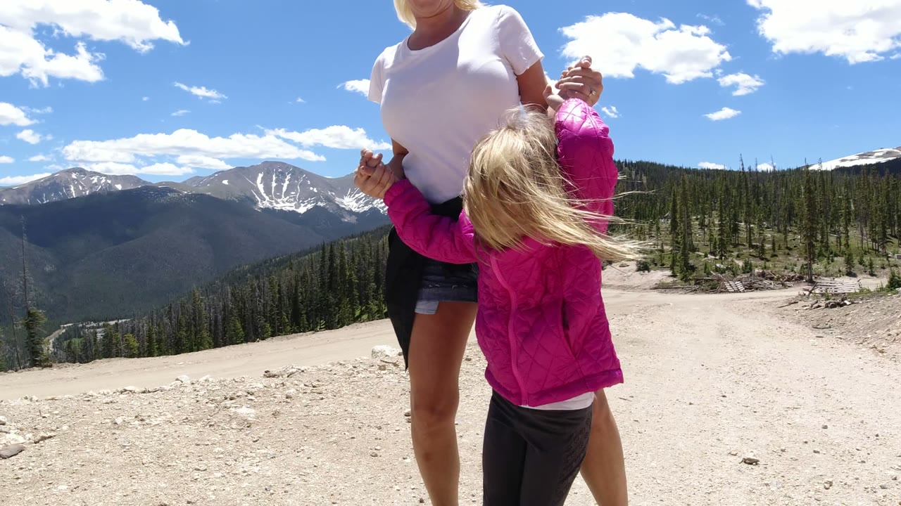 Woman and small child holding hands on a mountain path.