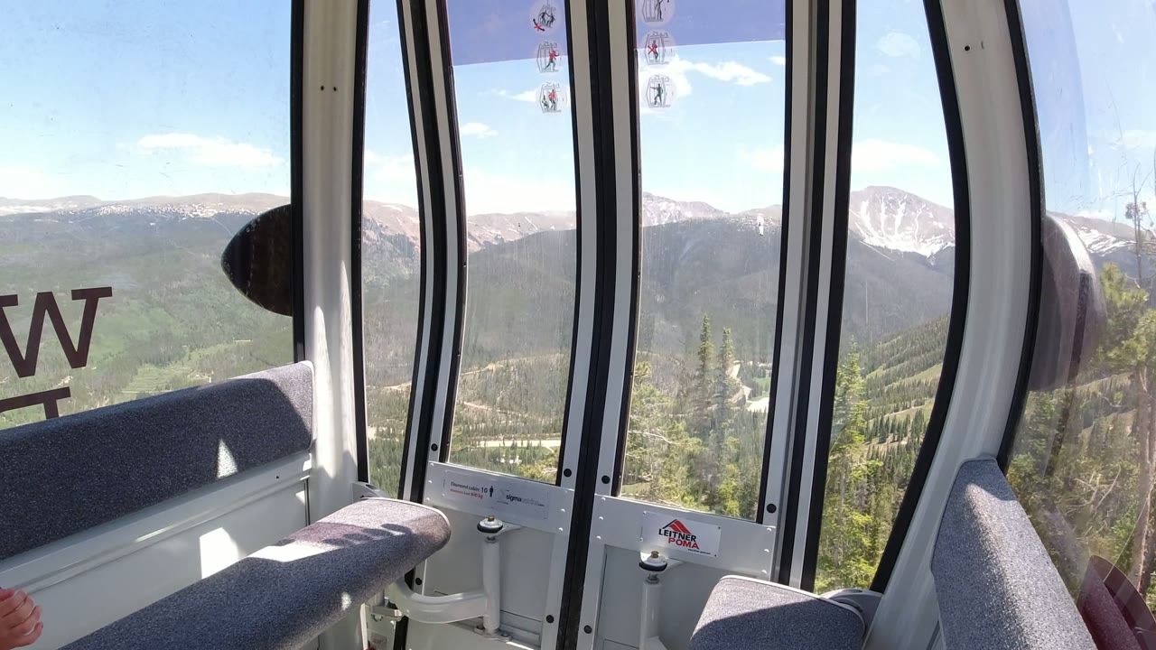 Interior ride car window looking toward forested mountains and snow-capped peaks.
