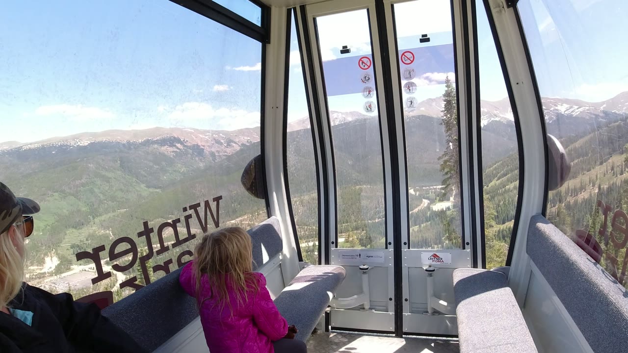 Woman and child inside a gondola with mountain ridges through the windows.
