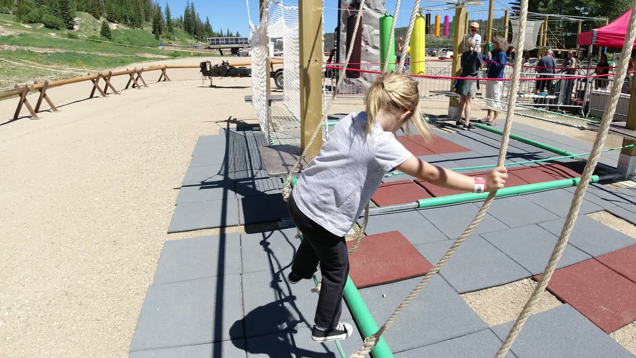 Blonde child stepping onto a playground rope balance feature