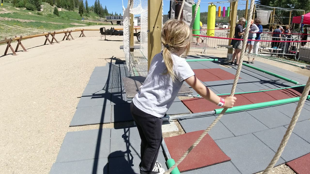 Girl holding rope swing lines at an outdoor obstacle course